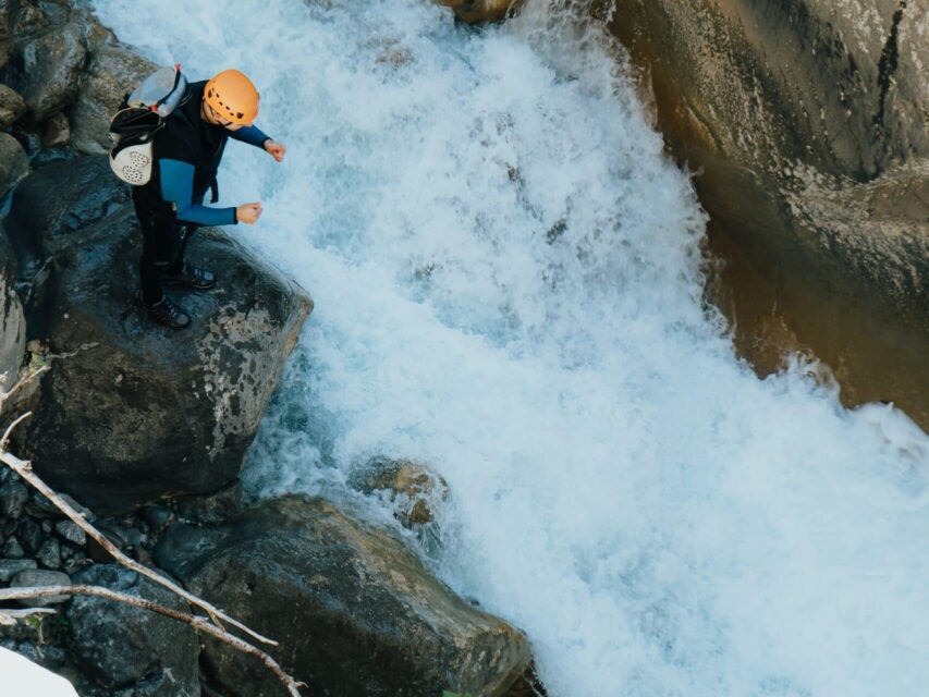 Beautiful top angle shot people doing extreme sports over a river ina stony mountain A beautiful top angle shot people doing extreme sports over a river ina stony mountain