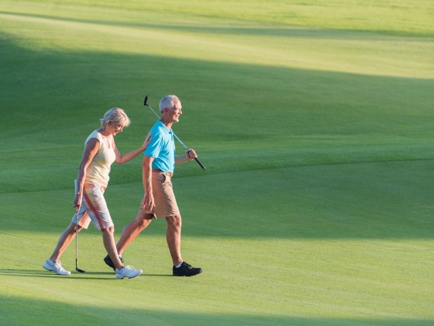couple senior sur un green de golf couple après 50 ans en tenue de golf avec leurs clubs marchant sur un green de golf