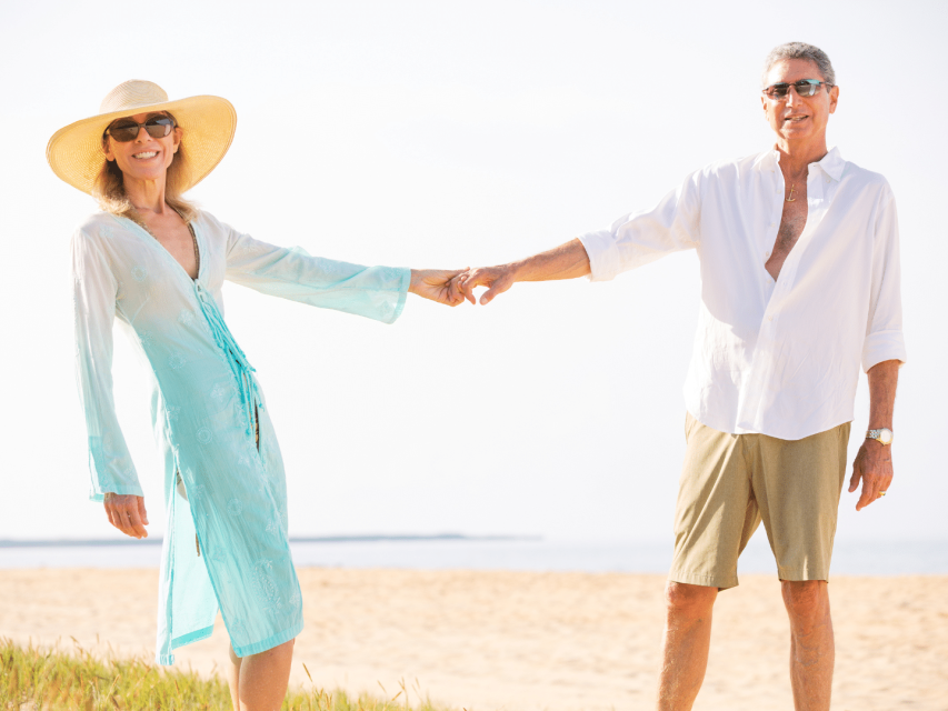 couple senior souriant en tenue décontractée se donnant la main sur une plage couple après 50 ans souriant en tenue décontractée se donnant la main sur une plage